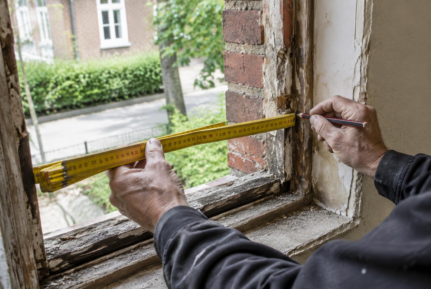 Håndværker måler et murhul op med tommestok